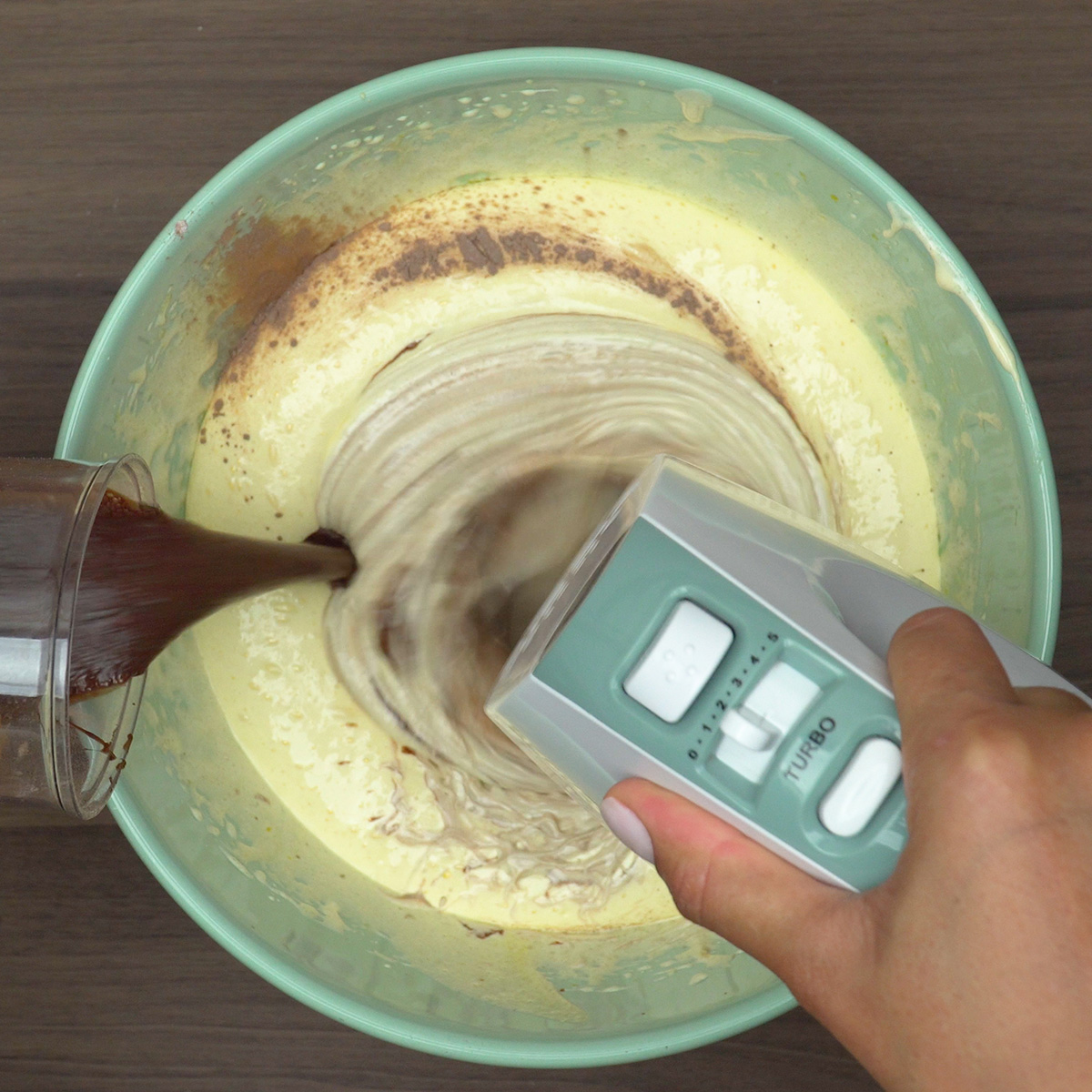 Mistura líquida sendo adicionada à massa de bolo de chocolate.
