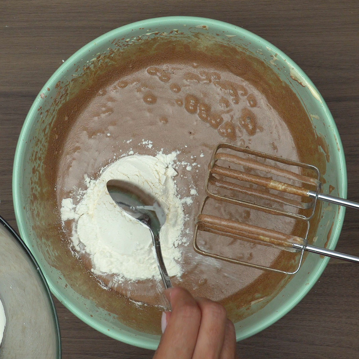 Farinha sendo adicionada à massa de bolo de chocolate.