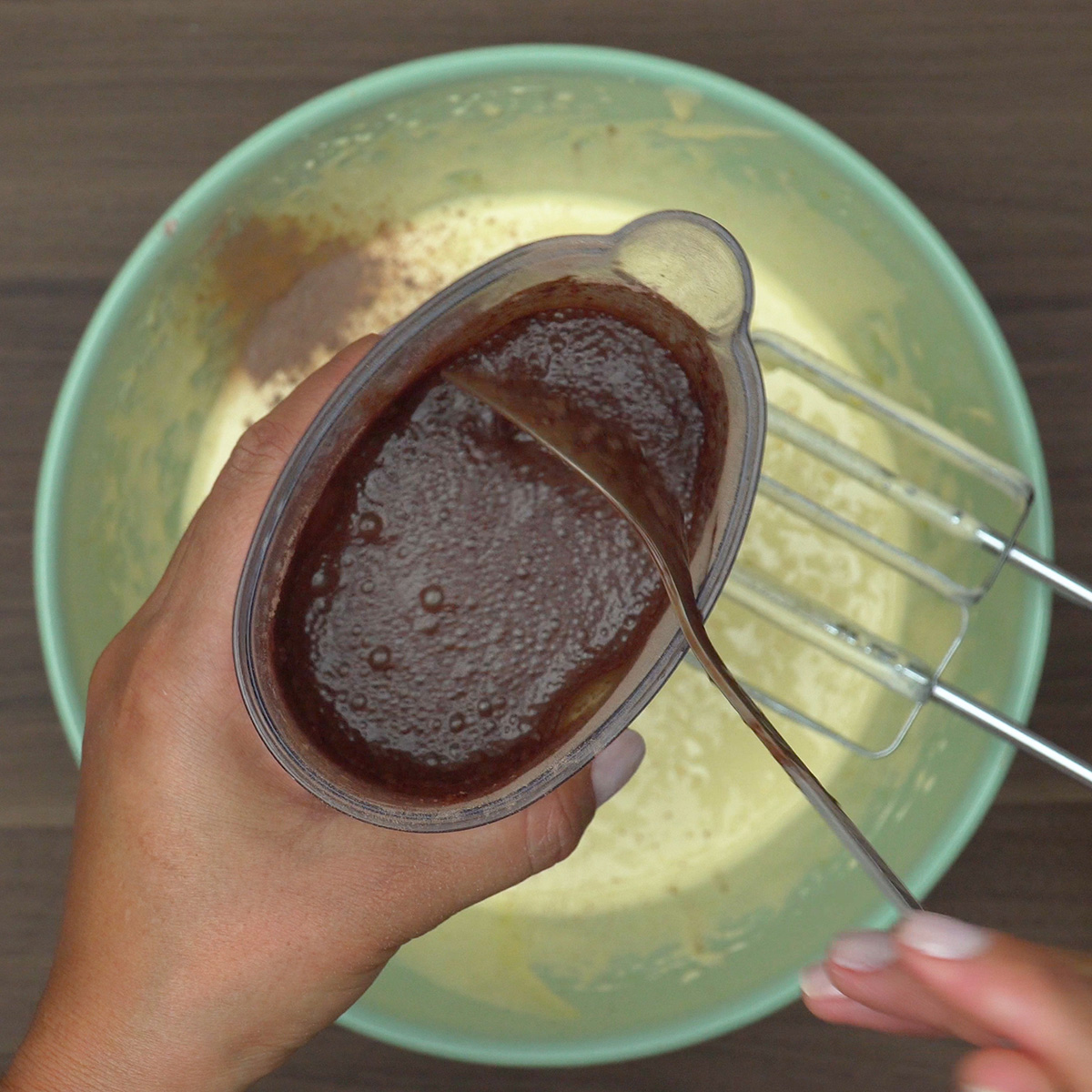 Mistura de leite morno com chocolate em pó sendo dissolvida.