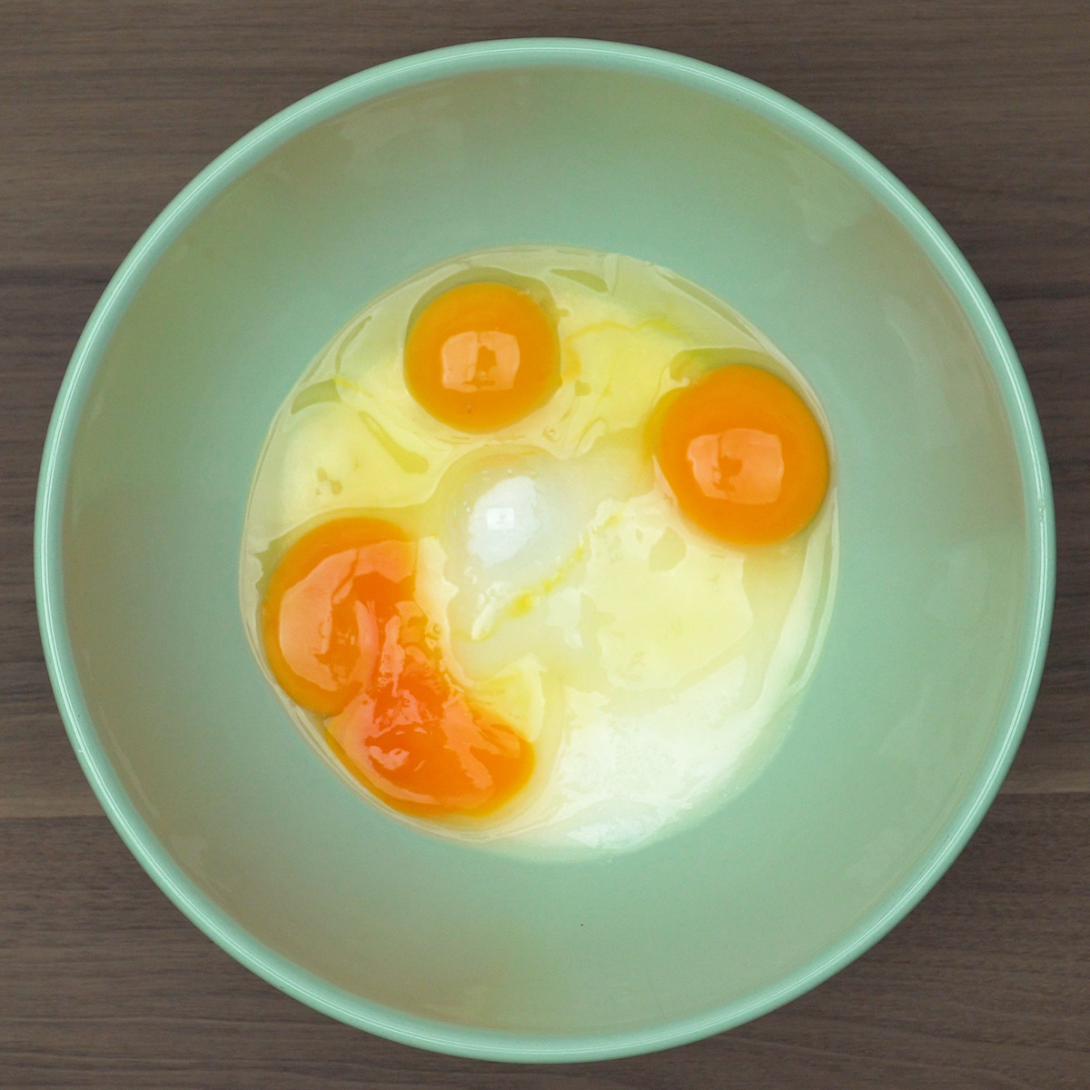 Ovos e açúcar sendo batidos até formar creme claro para bolo.