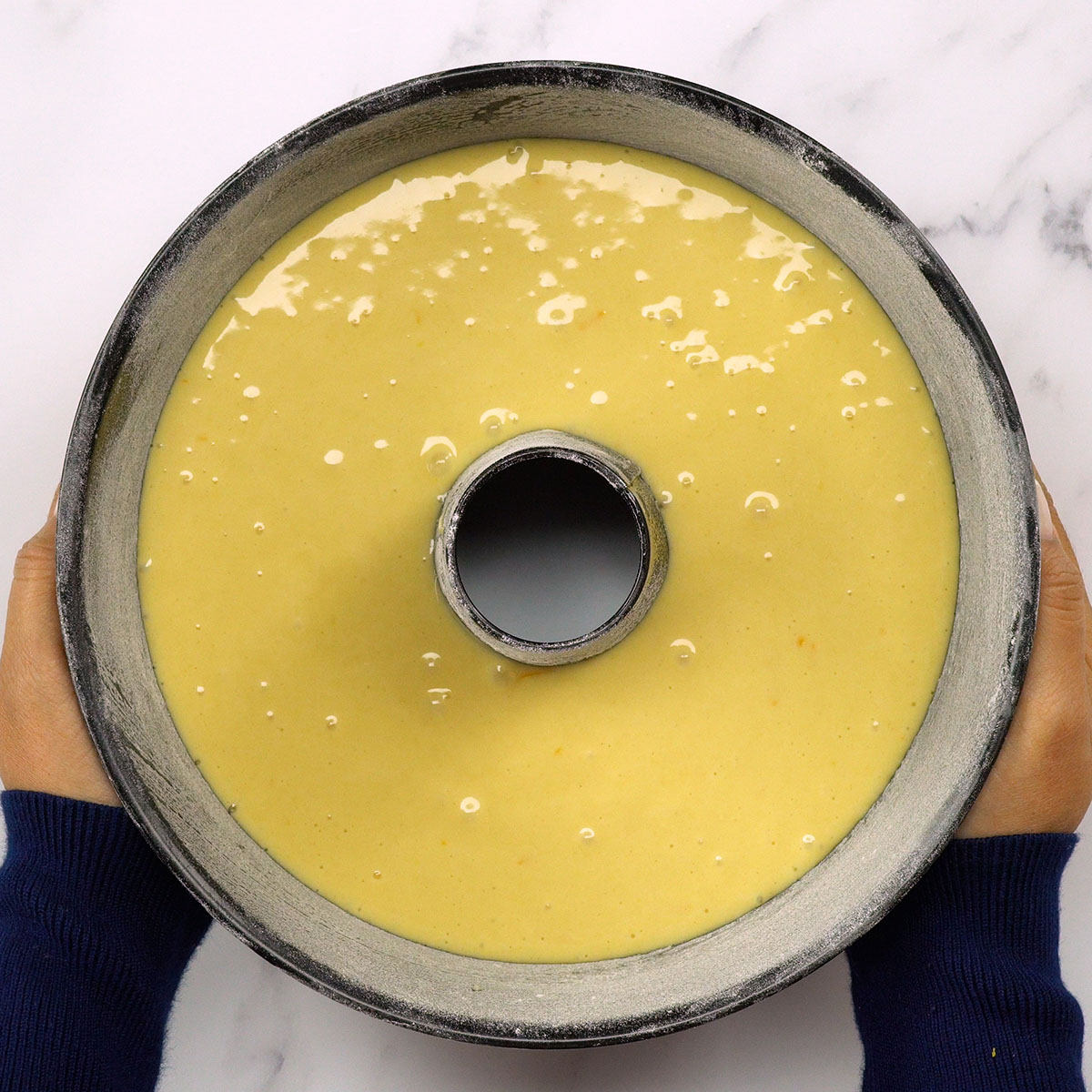 Bolo de laranja sendo levado ao forno para assar e dourar.