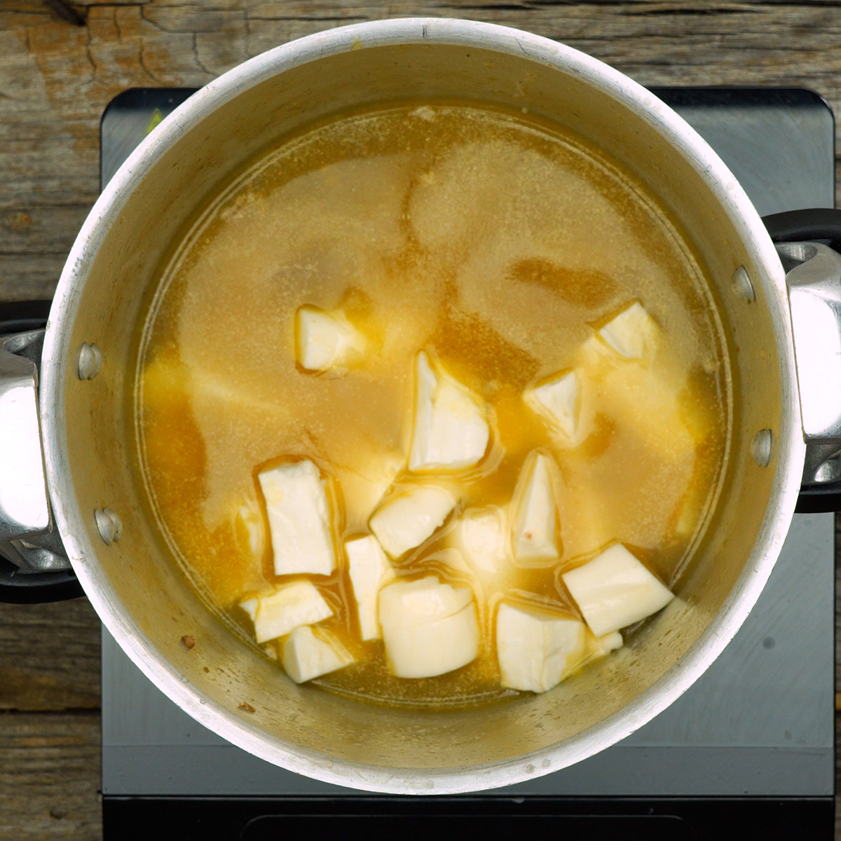 Pedaços de mandioca cozinhando no caldo da costela dentro da panela.