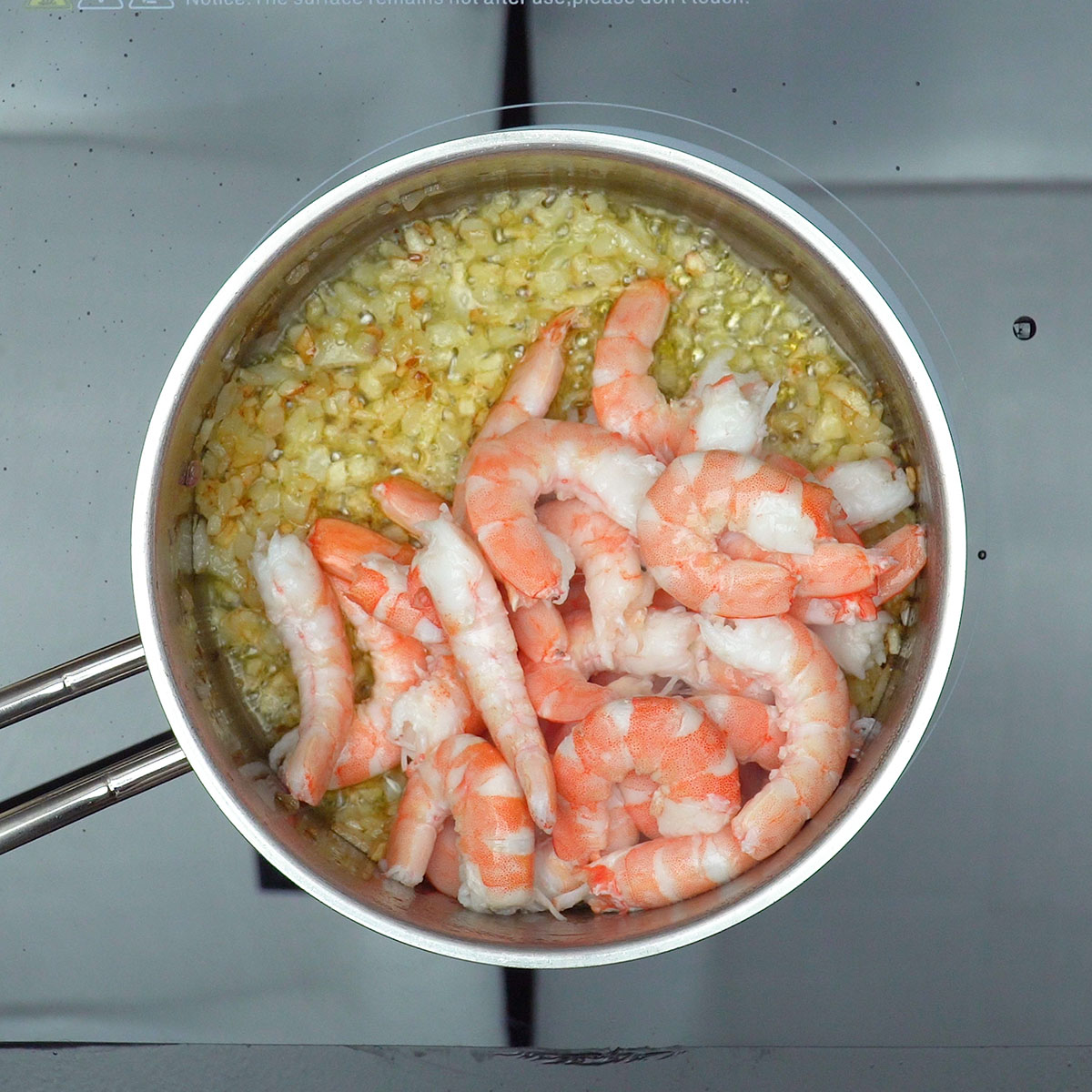 Camarões cozinhando na frigideira com temperos para receita gratinada.
