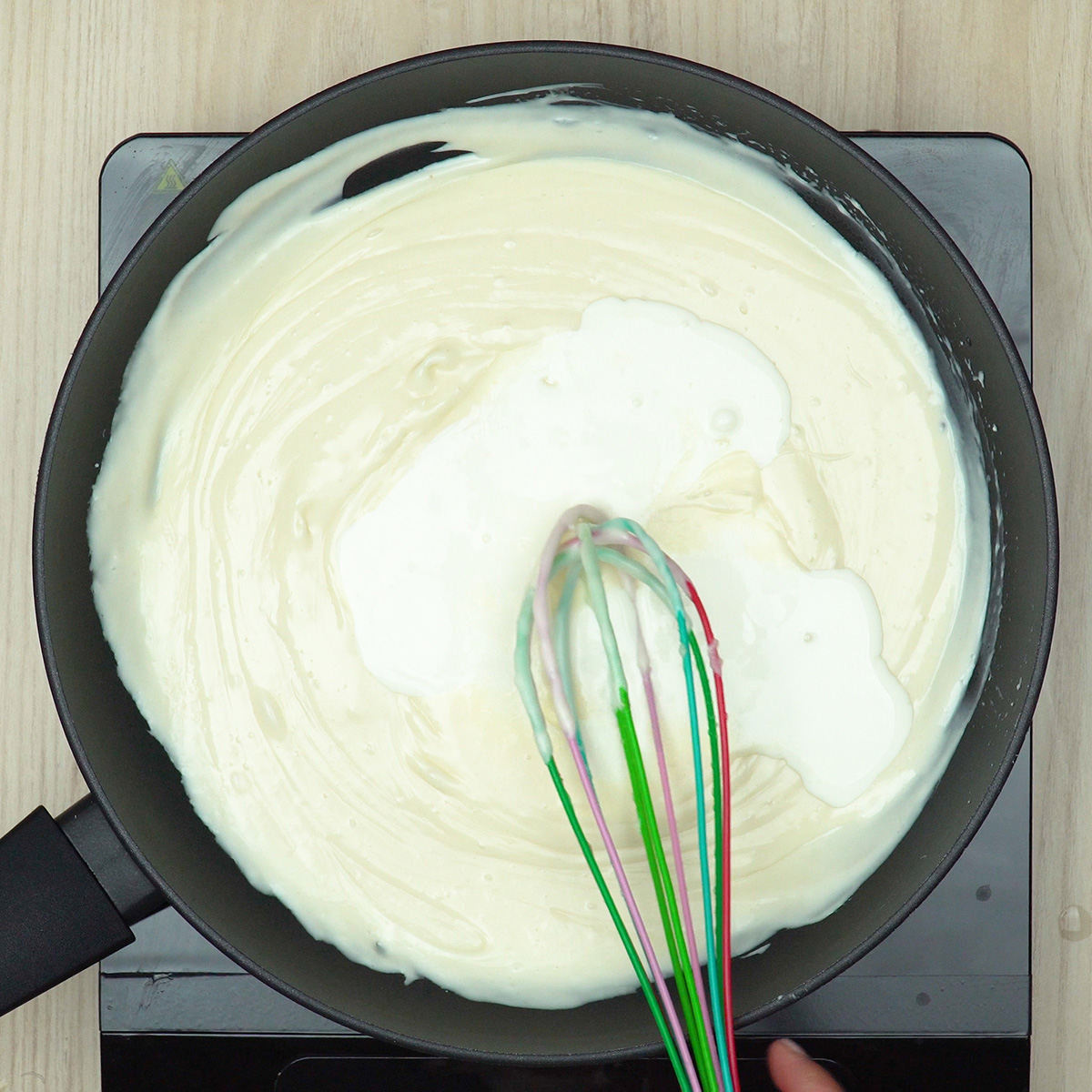 Creme de leite sendo incorporado ao molho branco cremoso.