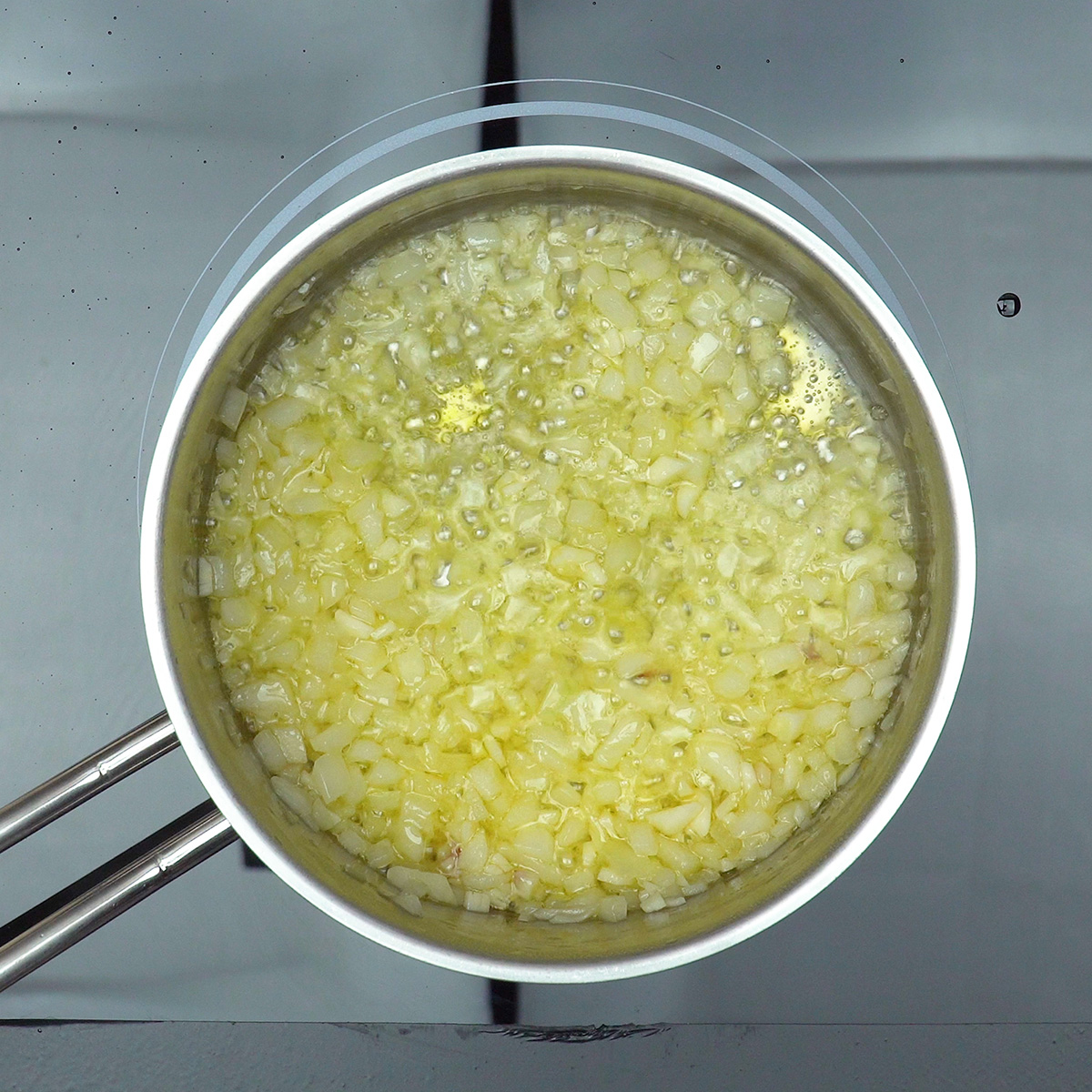 Cebola e alho refogados no azeite para preparar camarão gratinado.