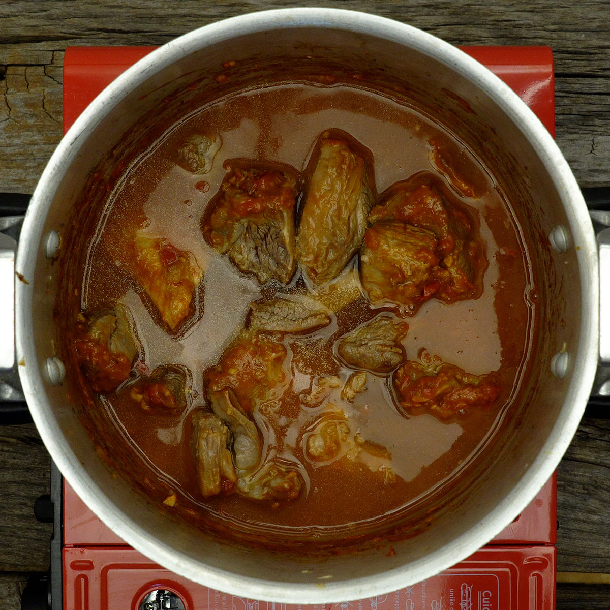 Carne cozinhando na pressão com molho de tomate.