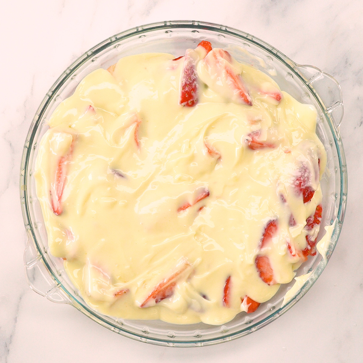 Creme branco espalhado sobre os morangos na travessa da sobremesa.