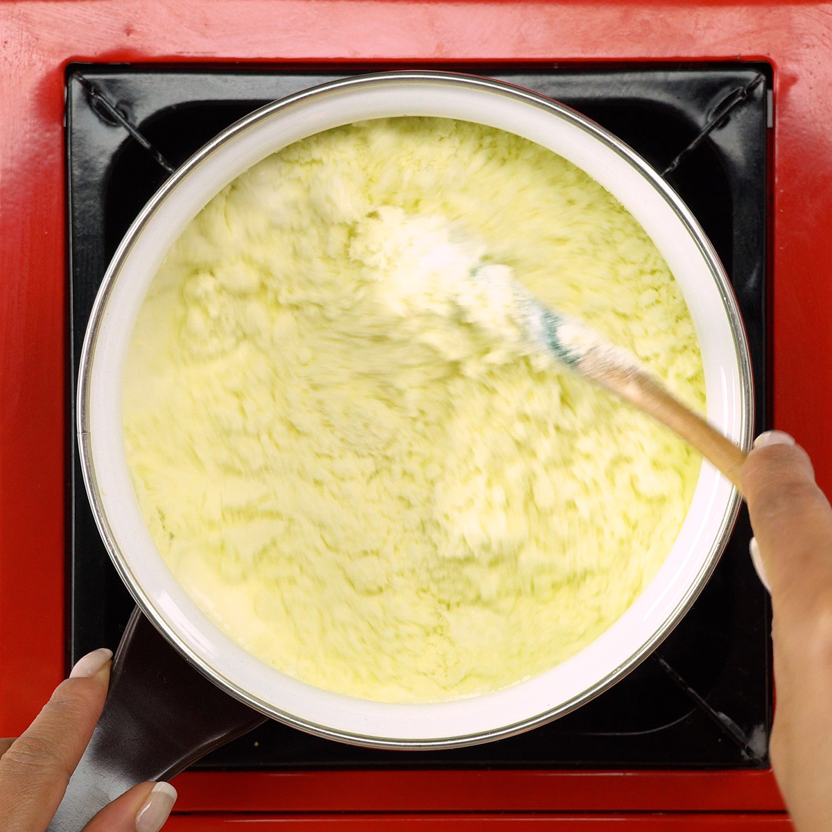 Creme branco sendo misturado na panela para preparar delícia de morango com ganache.