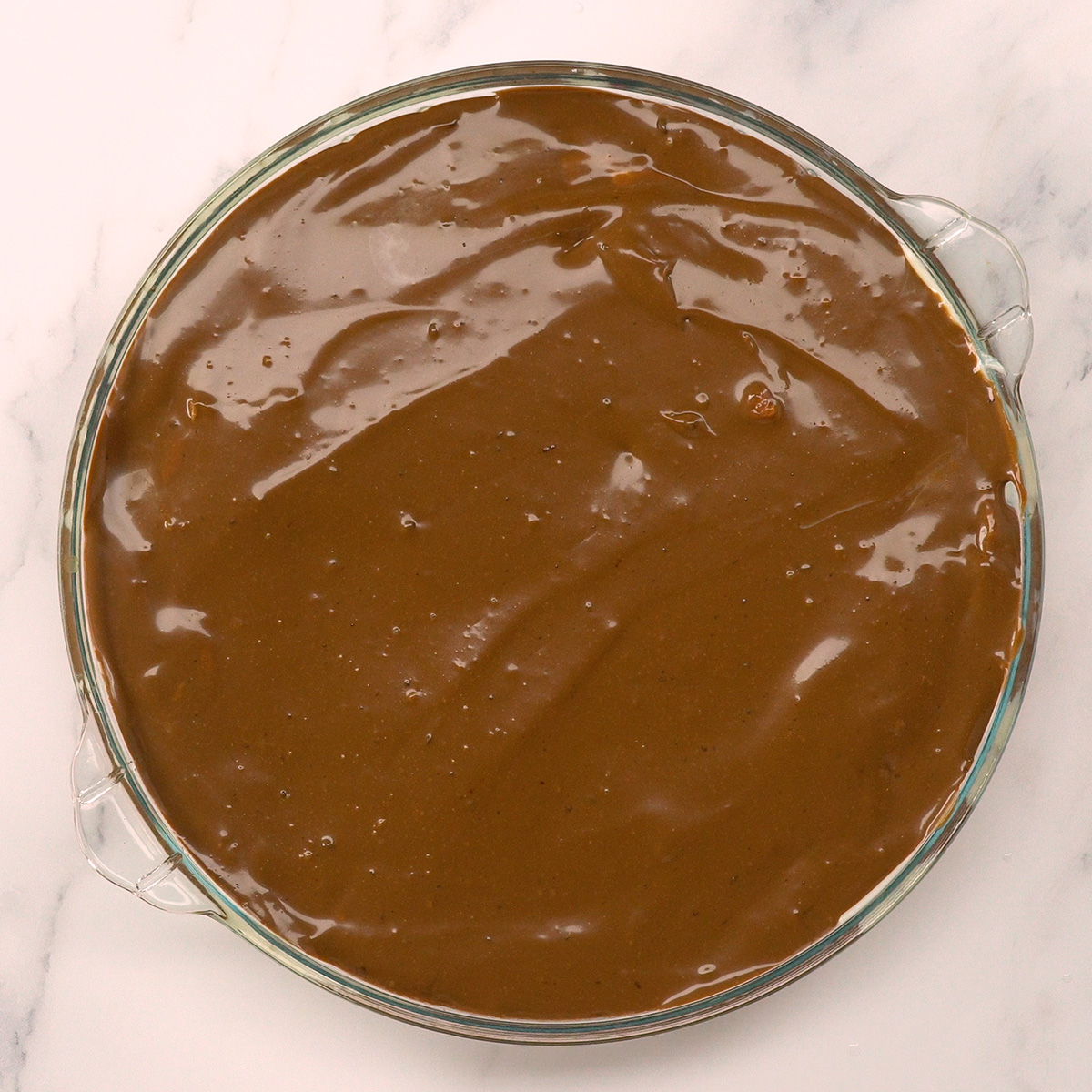 Ganache de chocolate cobrindo a delícia de morango na travessa.