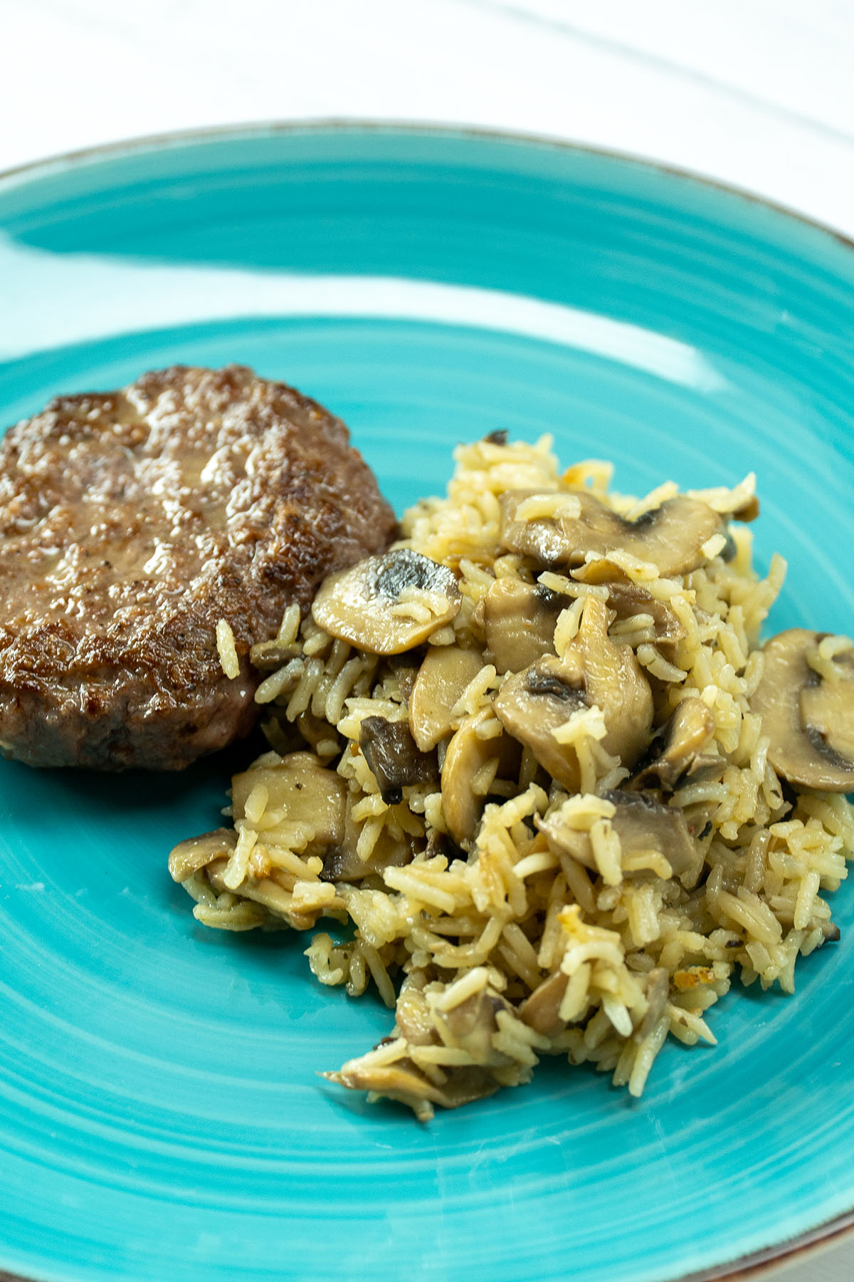Empratamento arroz de cogumelos com hambúrguer servido.