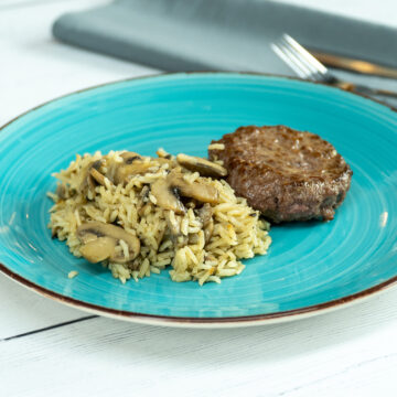 Empratamento arroz de cogumelos com hambúrguer servido.