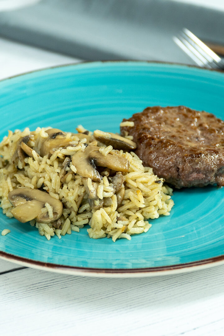 Empratamento arroz de cogumelos com hambúrguer servido.