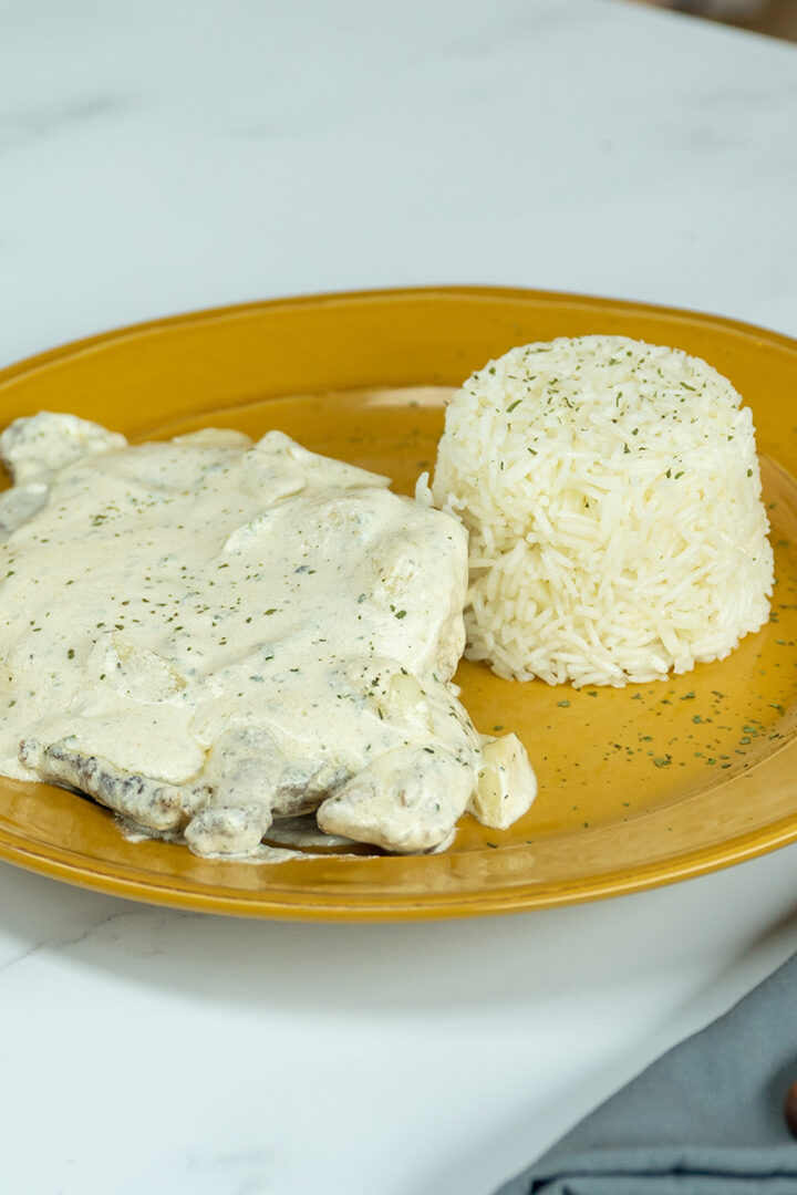 Empratamento bife ao molho de alho com arroz de acompanhamento.