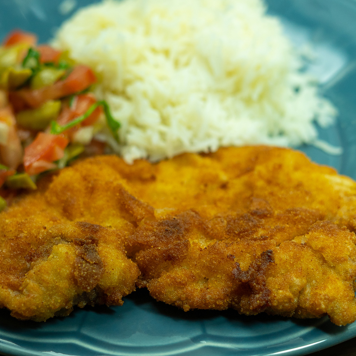 Empratamento bifes de porco panados crocantes com arroz e salada de acompanhamento.