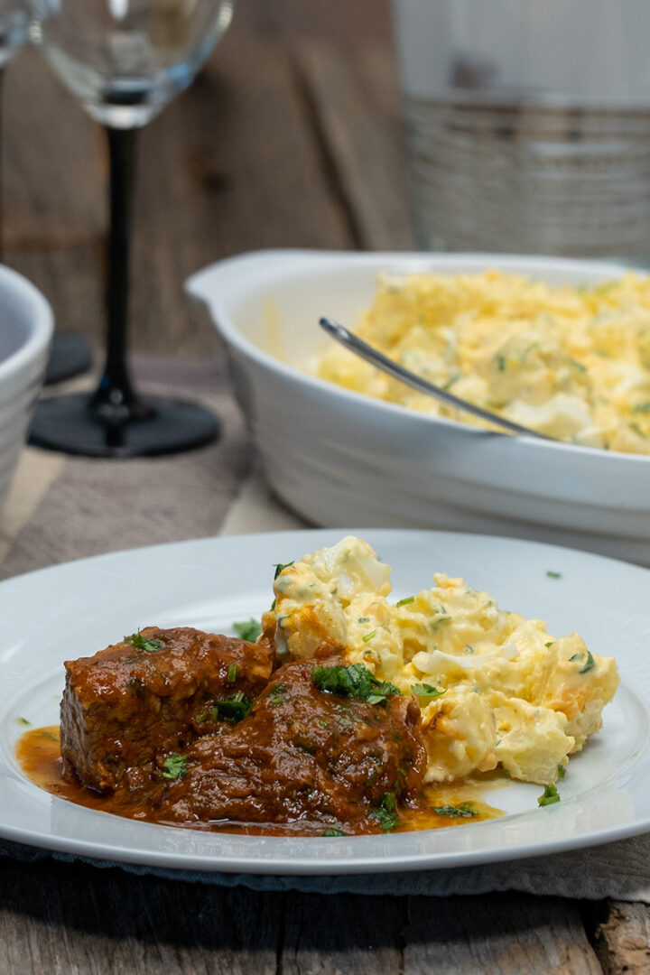 Empratamento carne cozida com salada de batata de acompanhamento finalizado coentro.