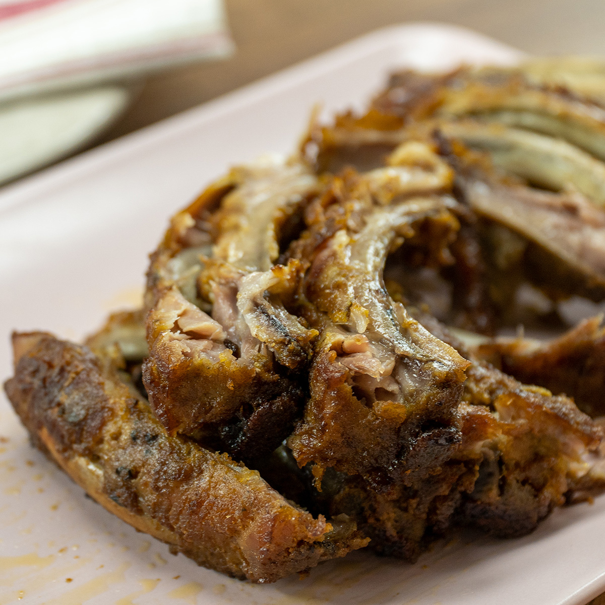Empratamento costelinha de porco no forno com cachaça sendo servido e cortado.