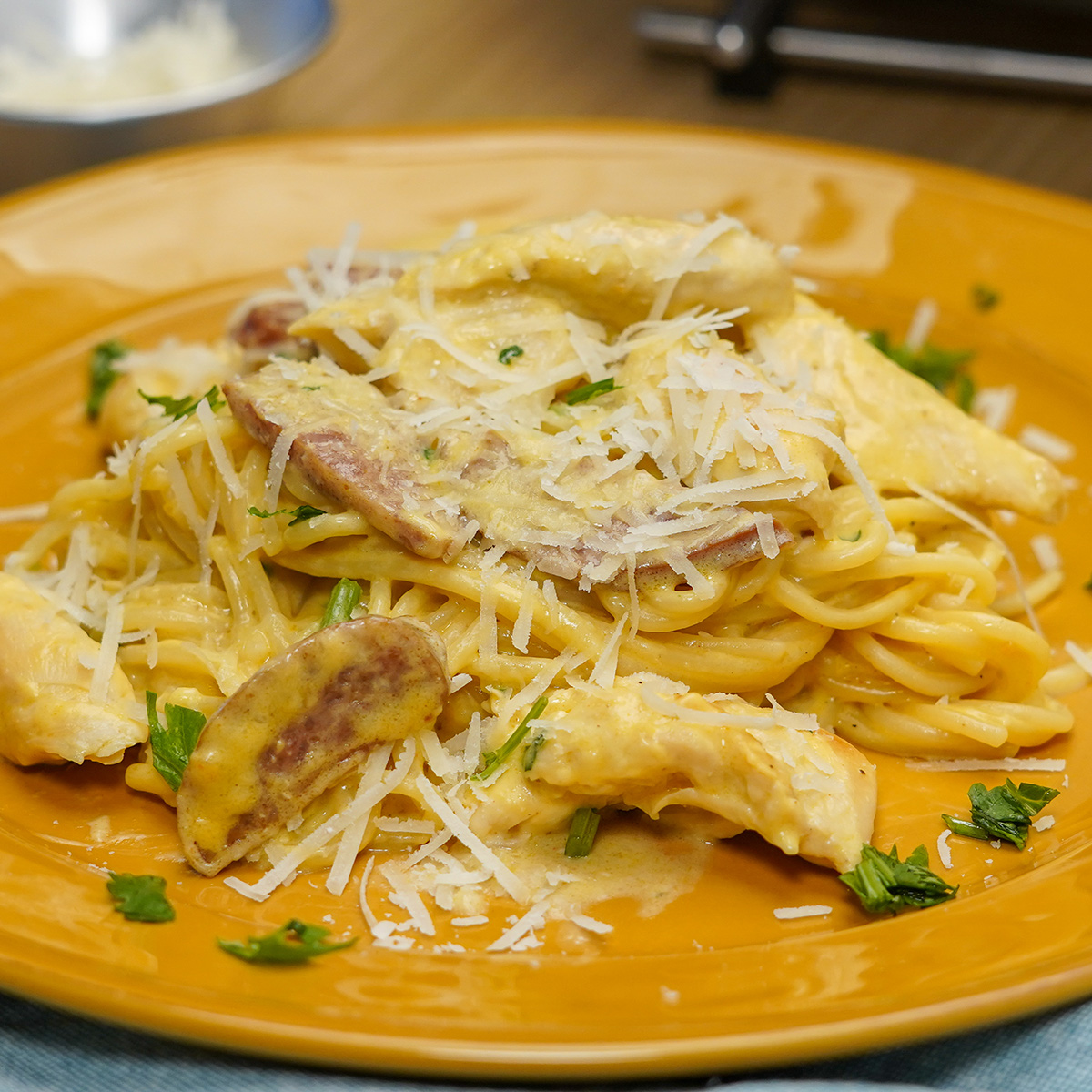 Empratamento espaguete com frango e calabresa ao molho cremoso pronto finalizado com salsa fresca.