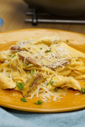 Empratamento espaguete com frango e calabresa ao molho cremoso pronto finalizado com salsa fresca.