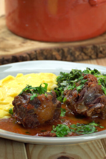 Empratamento rabada com polenta e agrião finalizada com salsa.