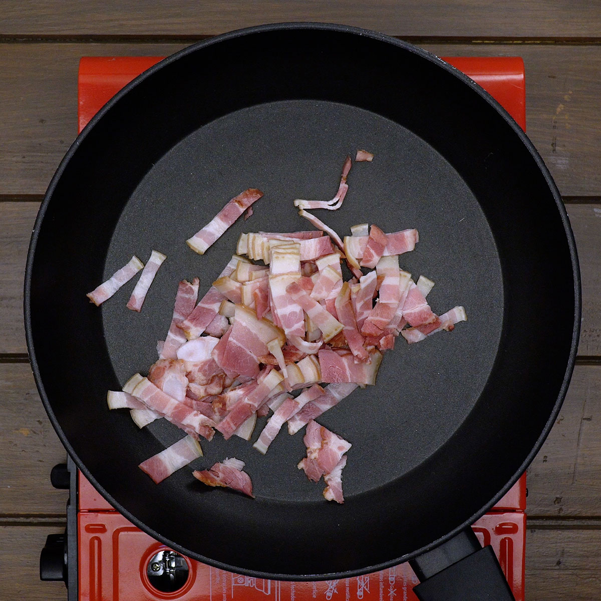 Bacon dourando lentamente em frigideira quente até ficar crocante e saboroso.