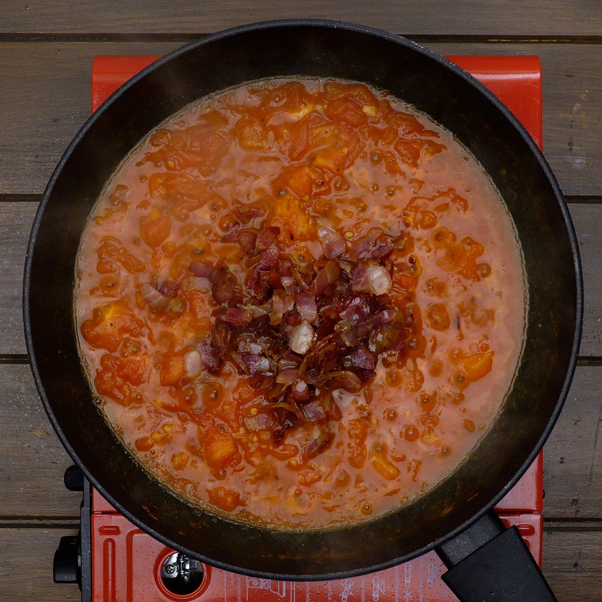 Bacon misturado ao molho de tomate na frigideira.