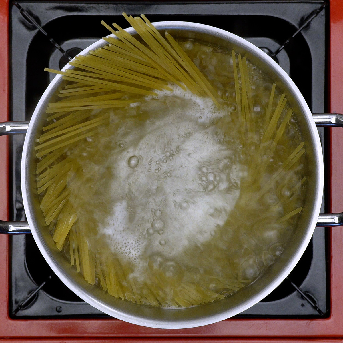 Espaguete cozinhando em panela com água fervente até atingir textura al dente.
