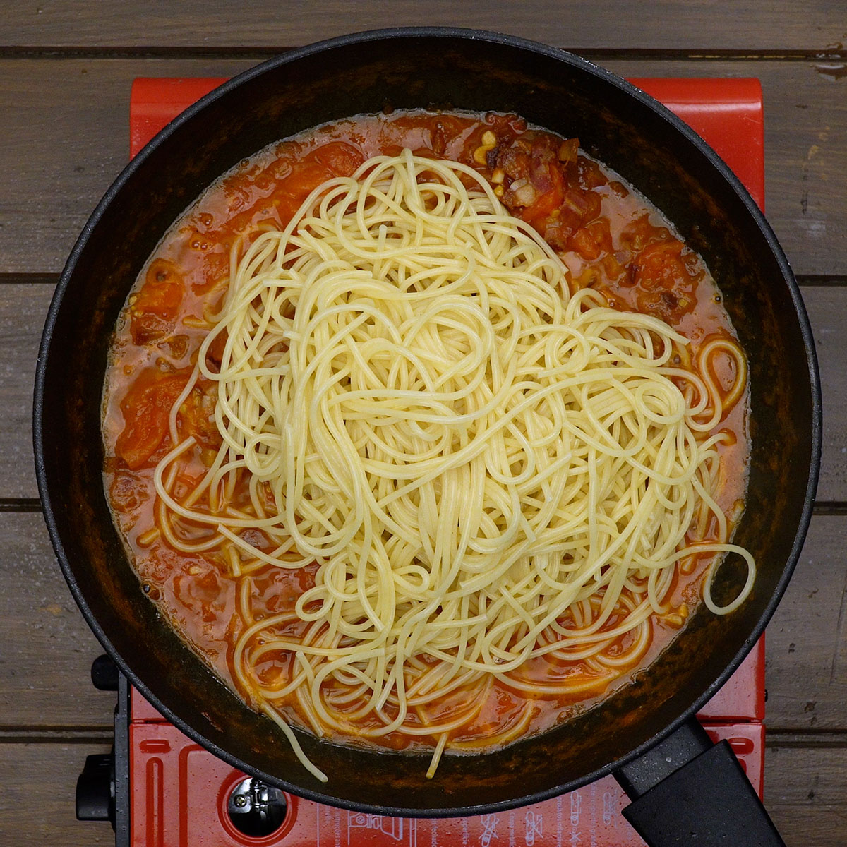 Espaguete envolvido no molho amatriciana dentro da frigideira.