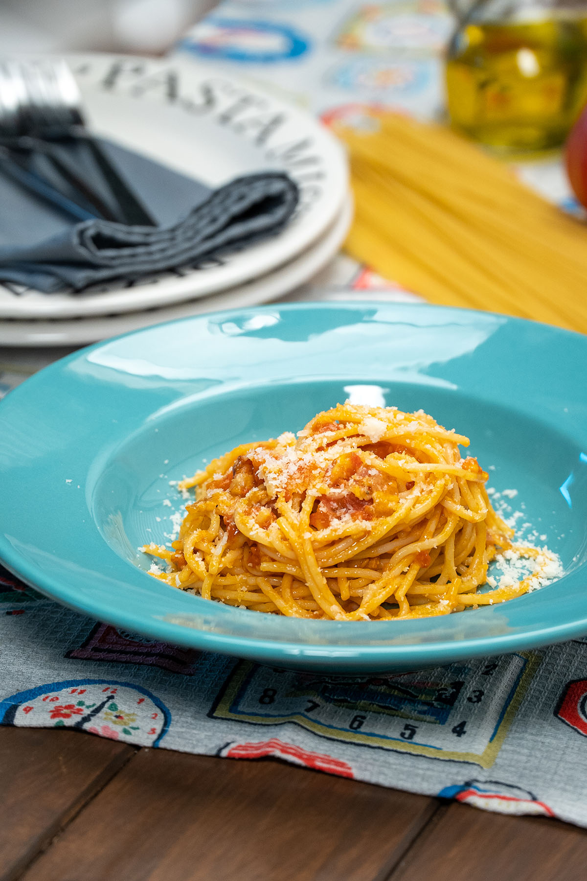 Empratamento espaguete amatriciana com queijo parmesão ralado por cima.