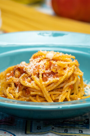 Empratamento espaguete amatriciana com queijo parmesão ralado por cima.
