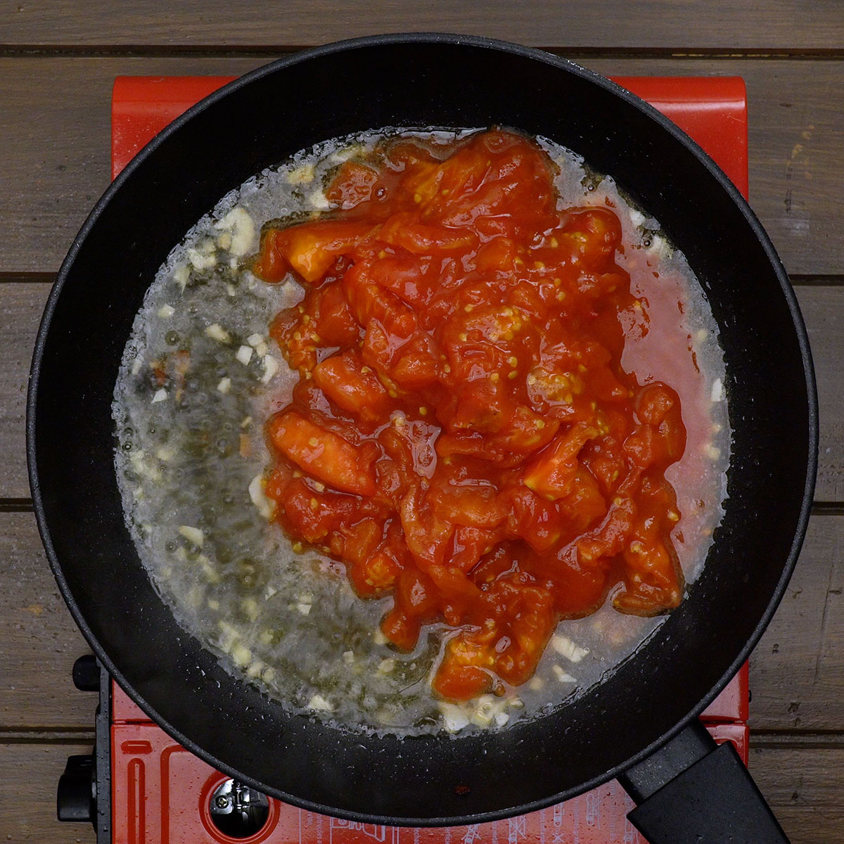 Tomate pelado com vinho branco em frigideira para espaguete amatriciana.