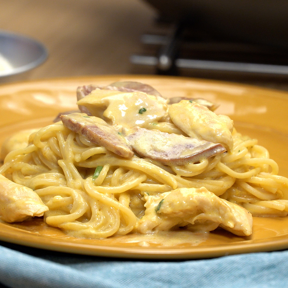 Espaguete cremoso com frango e calabresa servido com salsa fresca.
