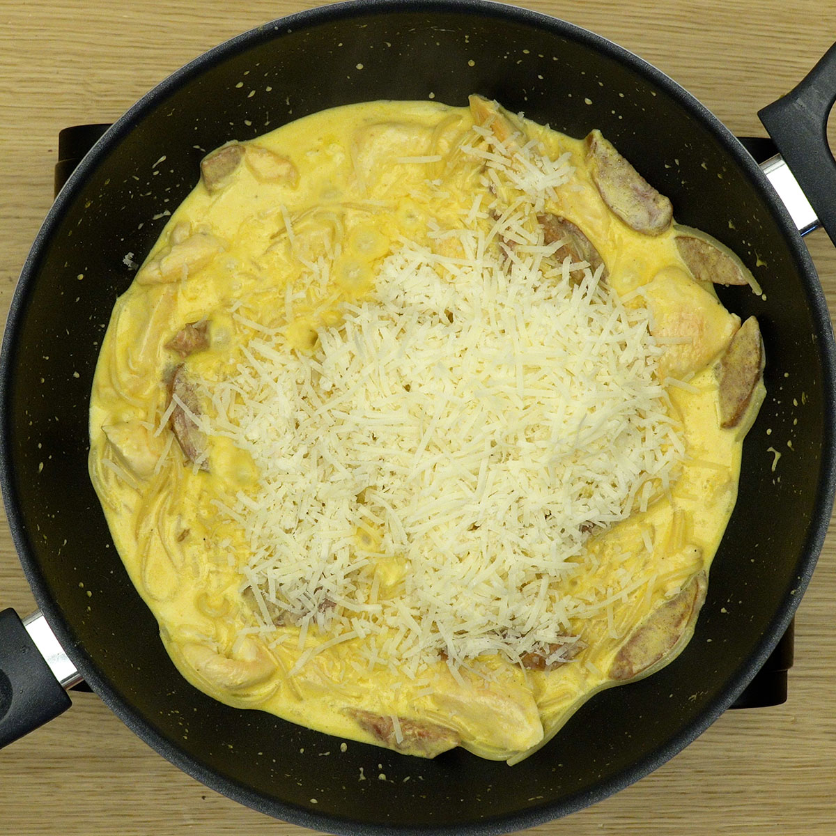 Queijo parmesão sendo misturado ao espaguete cremoso.