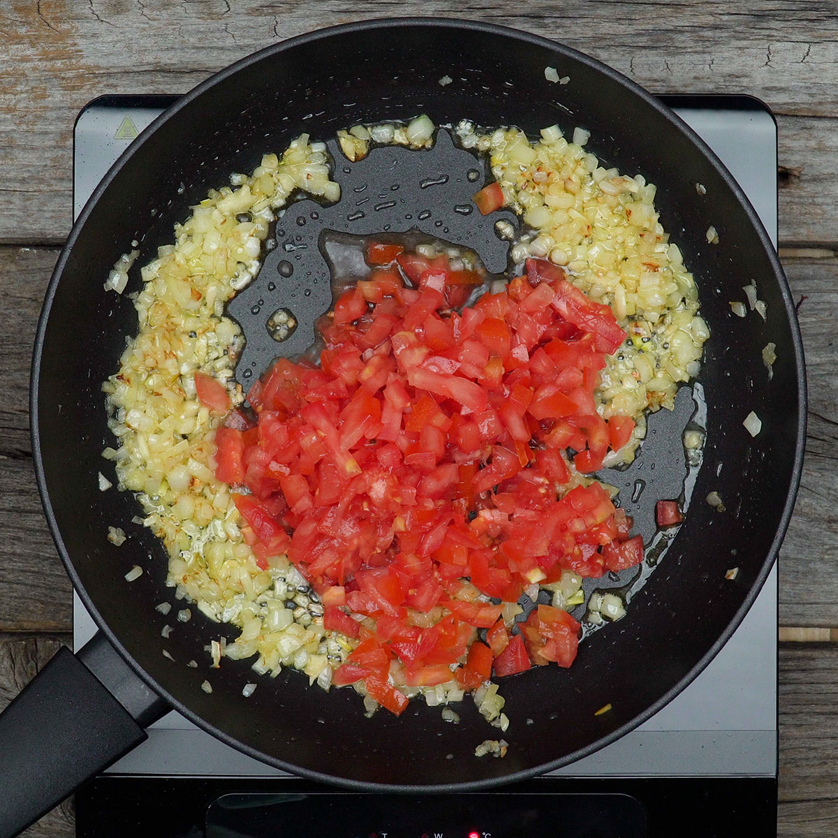 Tomate picado cozinhando até formar molho para massa de marisco.