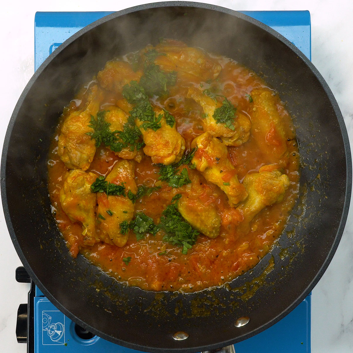 Asinhas de frango cozinhando com molho temperado e salsa fresca.