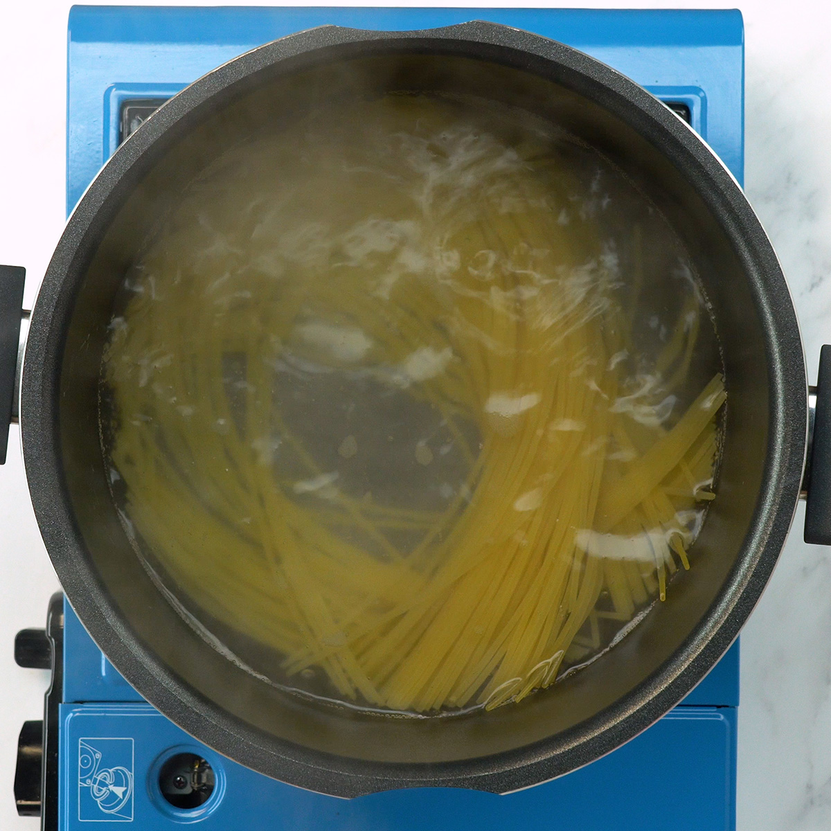 Espaguete cozinhando em panela com água fervente e sal.