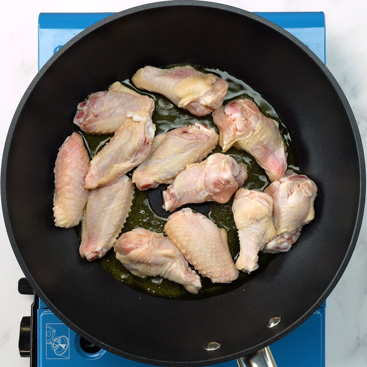 Asinhas de frango dourando no azeite.
