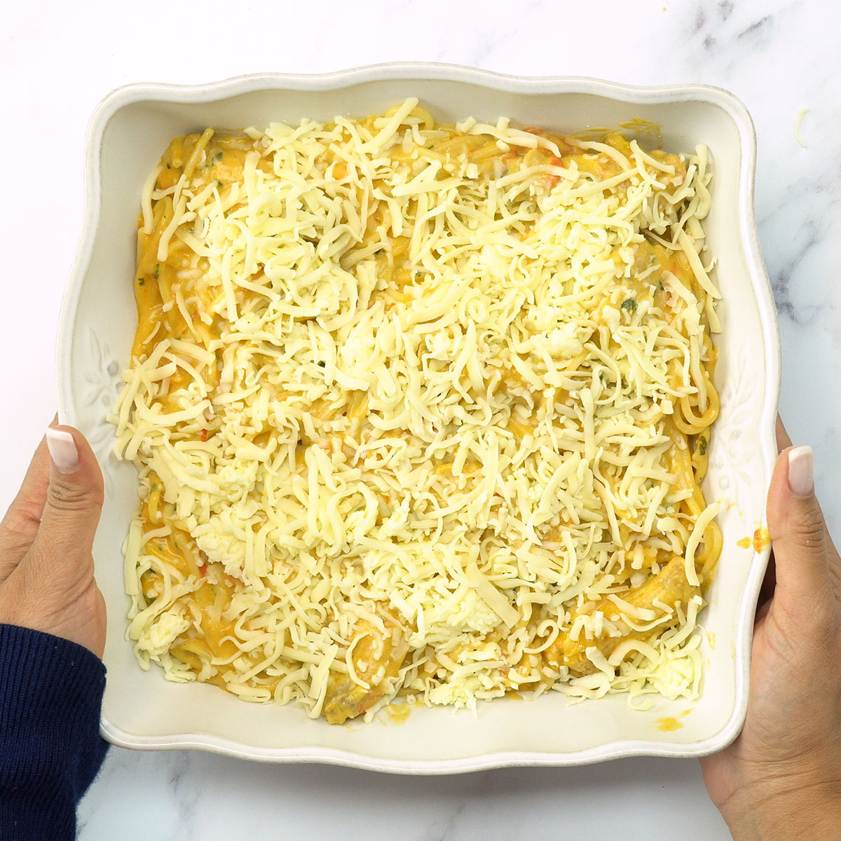 Espaguete gratinado coberto com muçarela antes de ir ao forno.