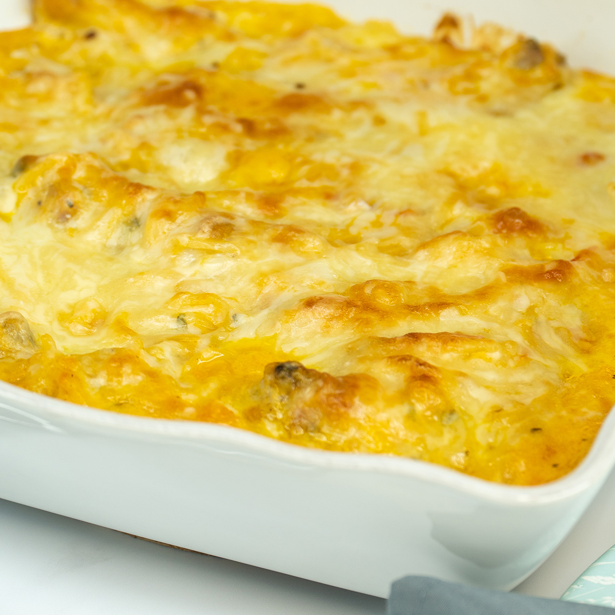 Espaguete gratinado com asinhas de frango na travessa pronto para ser servido.