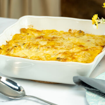 Espaguete gratinado com asinhas de frango na travessa pronto para ser servido.