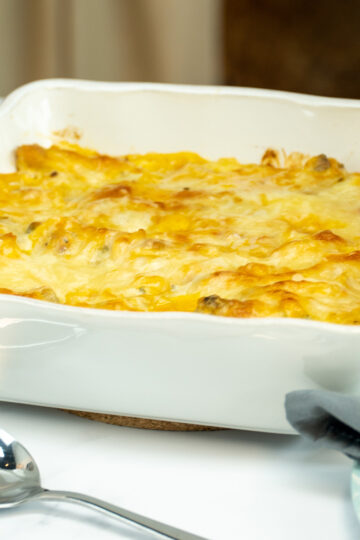 Espaguete gratinado com asinhas de frango na travessa pronto para ser servido.