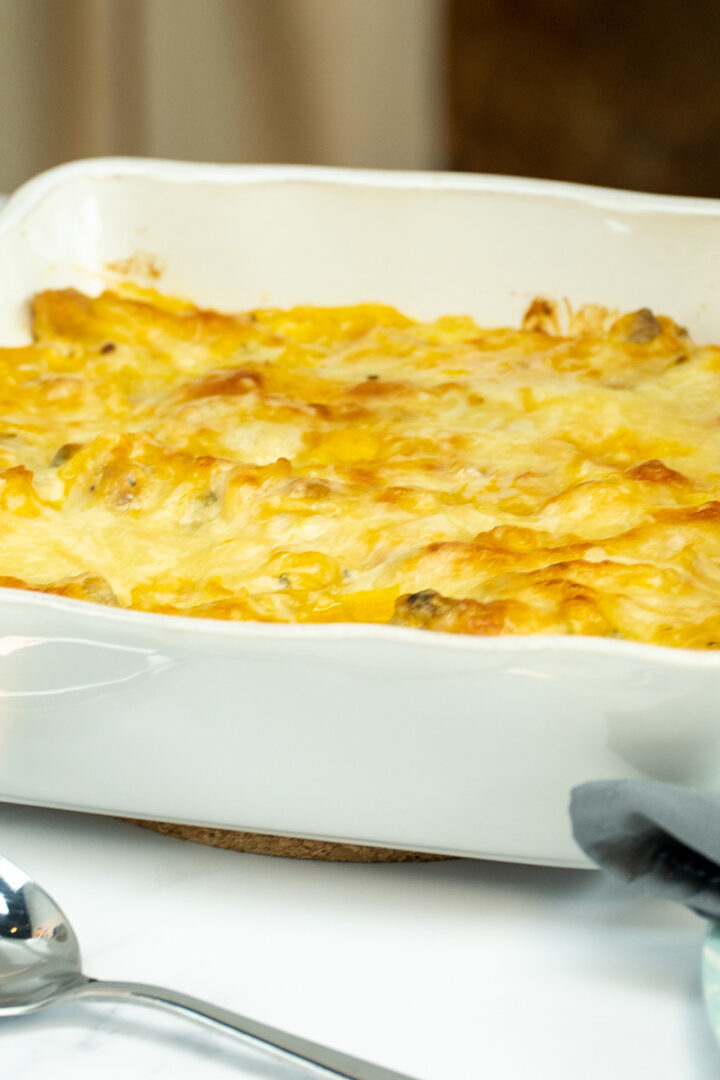 Espaguete gratinado com asinhas de frango na travessa pronto para ser servido.