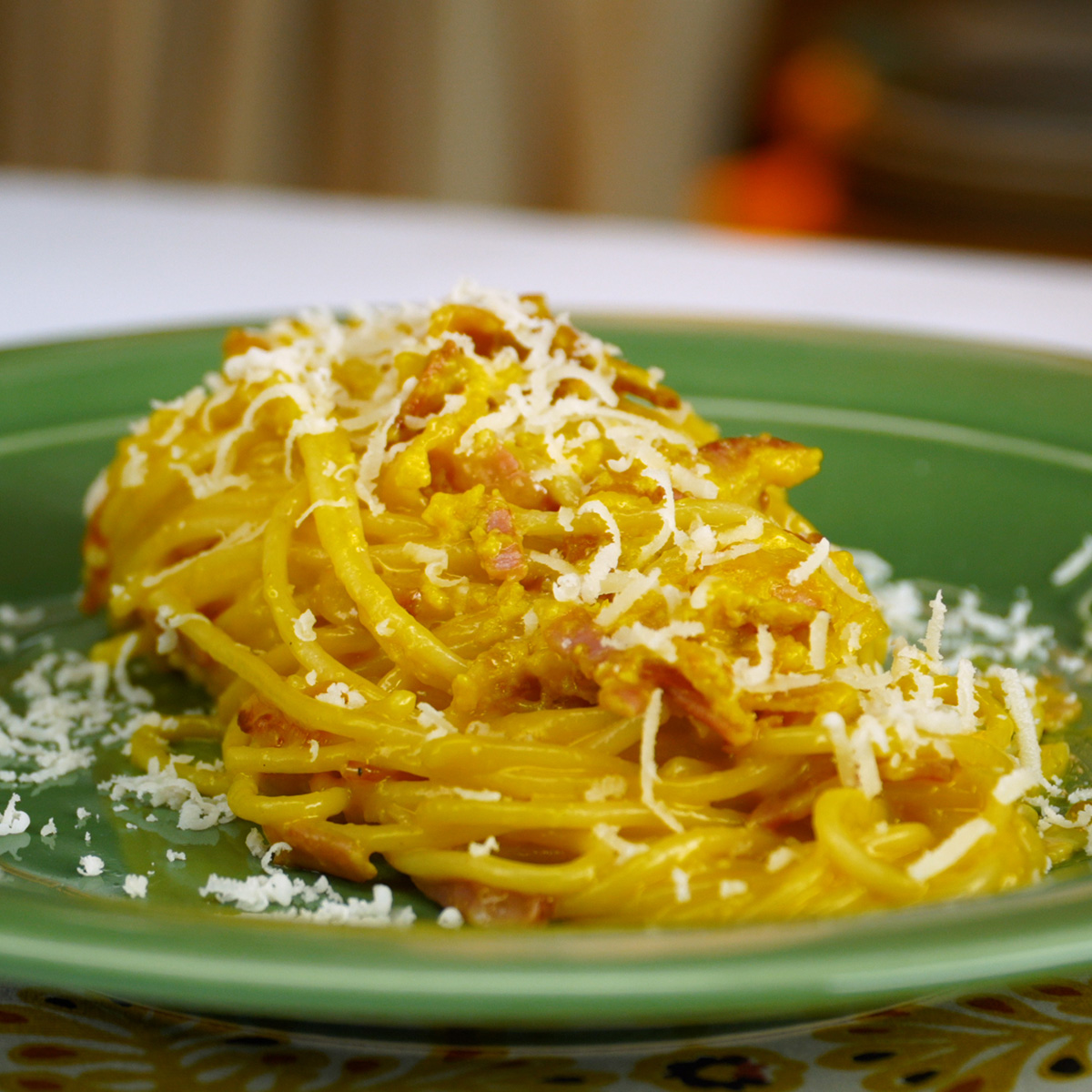 Espaguete à carbonara servido com queijo parmesão ralado por cima.