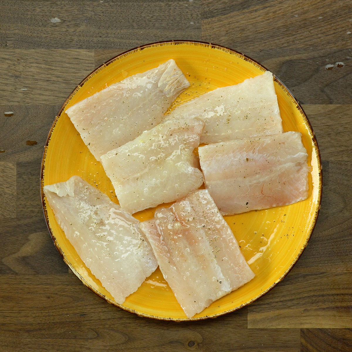 Filetes de pescada temperados com limão siciliano, sal e pimenta antes do preparo.