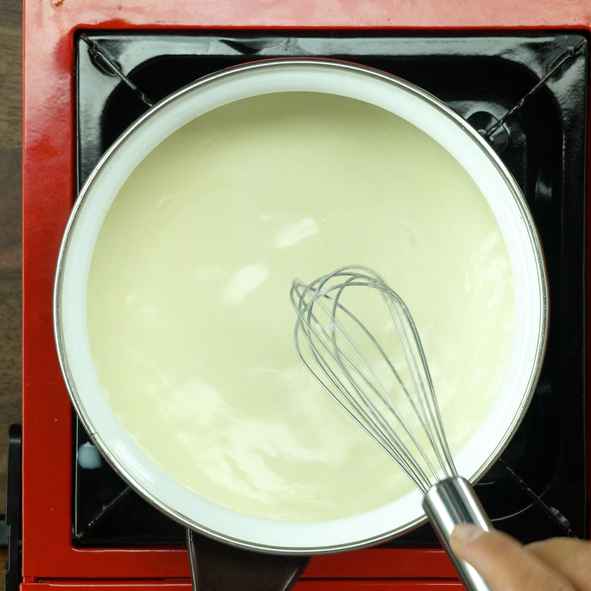 Molho branco cremoso sendo preparado na panela com manteiga e leite.