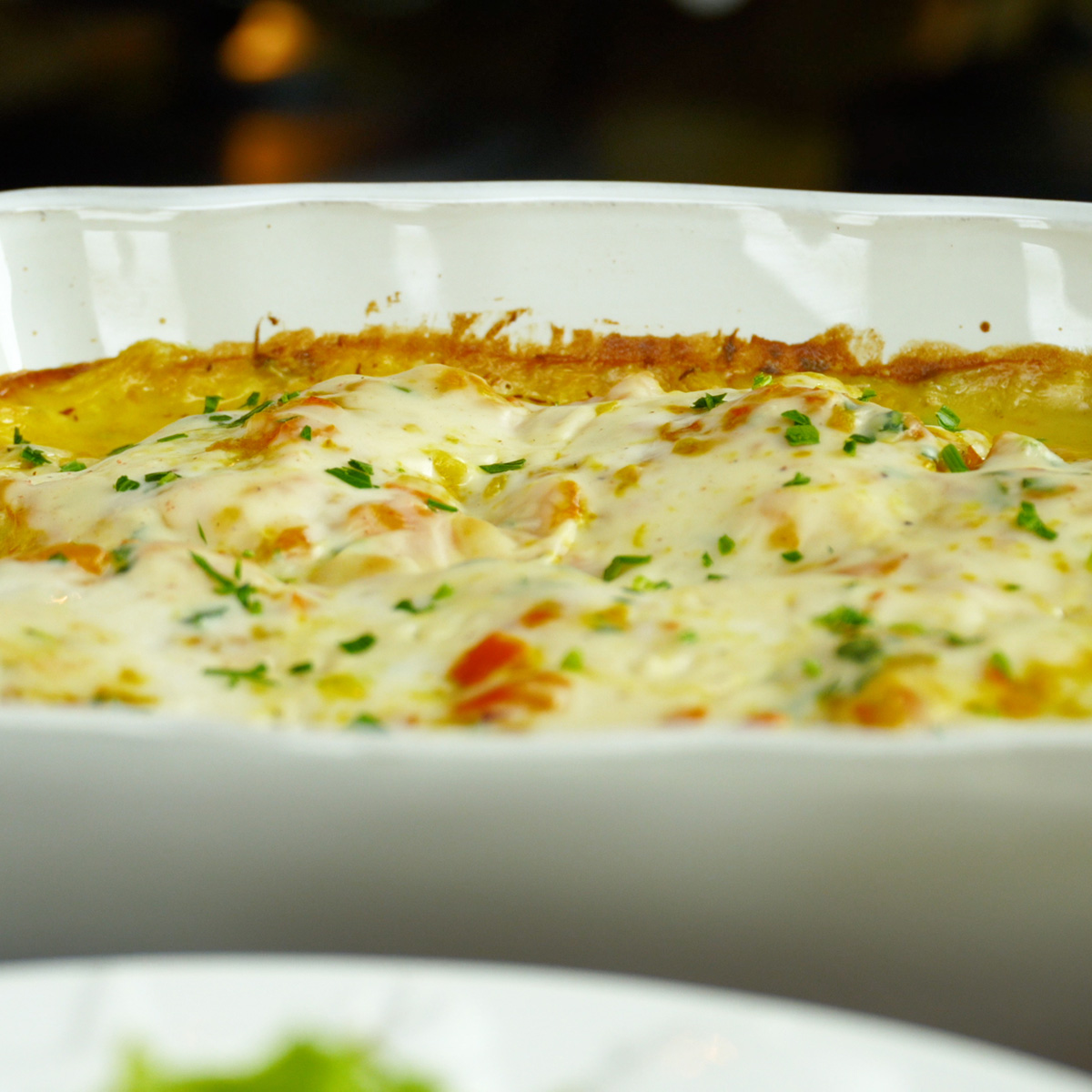 Filetes de pescada ao forno servidos com molho branco cremoso e salsa fresca.