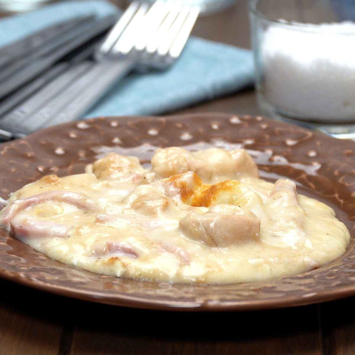 Frango com presunto ao molho branco gratinado servido no prato.