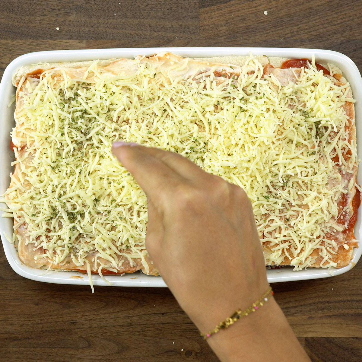 Cobertura de queijo ralado sobre o lachão de pizza antes do forno.