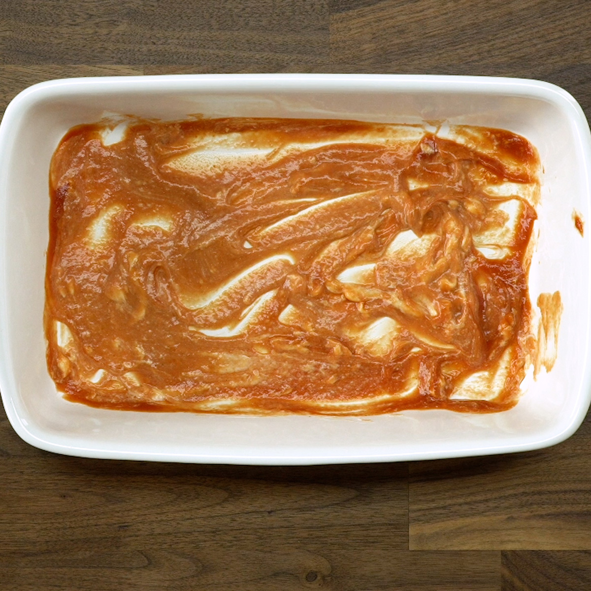 Molho de tomate e maionese espalhados no fundo da travessa para lachão de pizza.