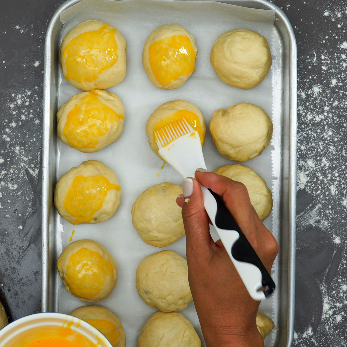 Pãezinhos recheados pincelados com gema antes de assar.