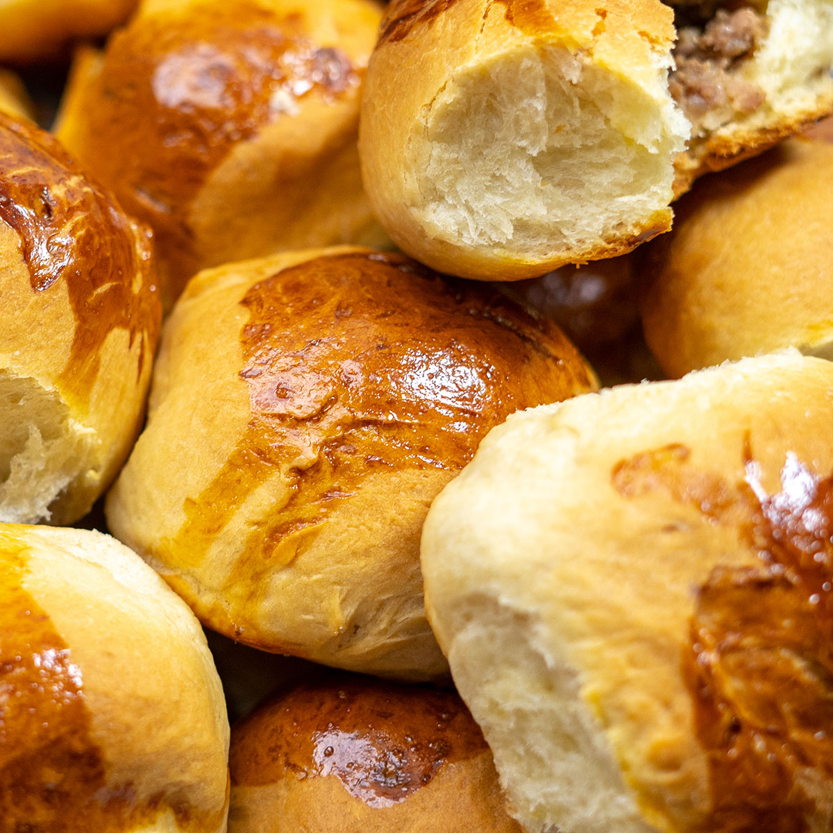 Pãezinhos assados recheados com carne moída prontos e sendo servidos.